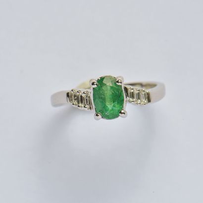 null 18K (750/oo) white gold cross ring centered on an oval emerald set with baguette-cut...