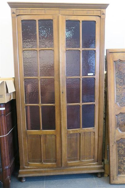 null Bibliothèque en bois naturel à décor mouluré et ouvrant à deux portes vitrées....