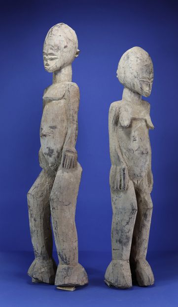  Important couple de statues, les têtes ovoïdes enserrant des petits visages aux...