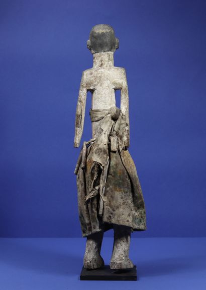 null 
Statue en bois représentant un personnage debout habillé d'une jupe en tissu...