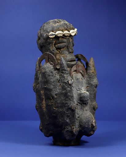 null 
Statue of a fetishist representing a wooden figure wearing a crown of cowries,...