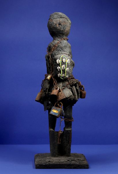 null 
Wooden votive statue representing a character standing on a truncated cone...