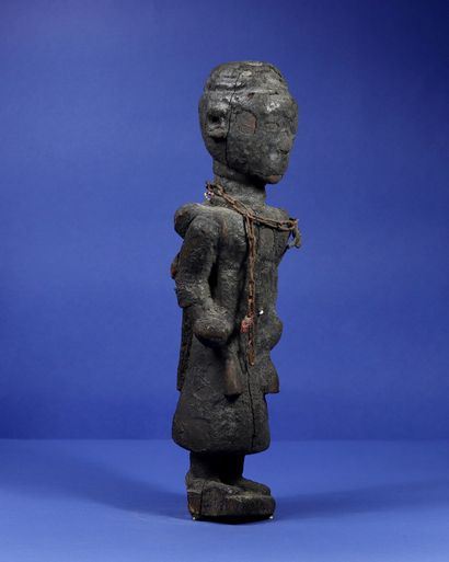 null 
Wooden votive statue representing an officiant in robes, holding ritual instruments...