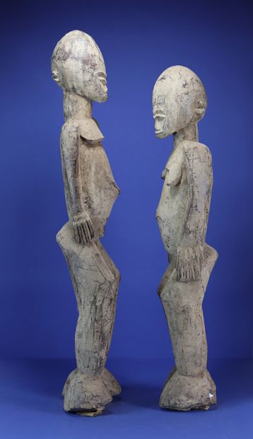  Important pair of statues, the ovoid heads enclosing small faces with fine features,...