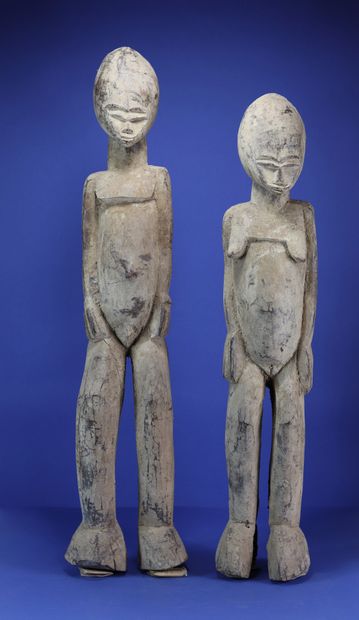 Important couple de statues, les têtes ovoïdes enserrant des petits visages aux...