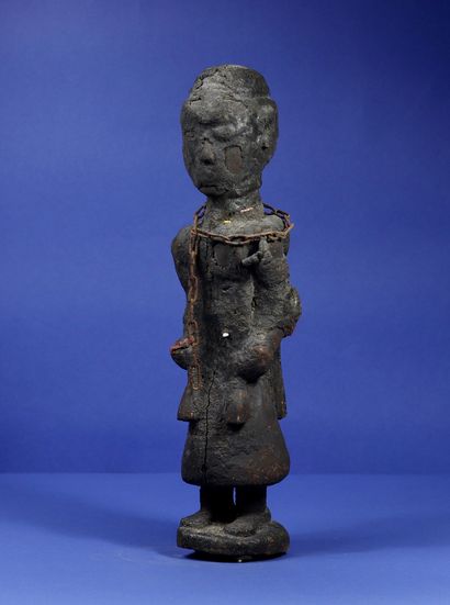 null 
Wooden votive statue representing an officiant in robes, holding ritual instruments...