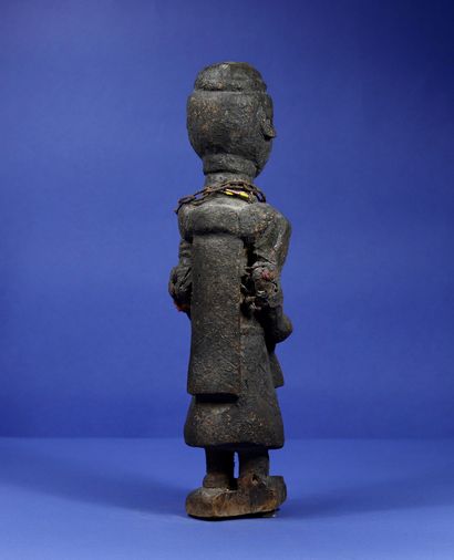 null 
Wooden votive statue representing an officiant in robes, holding ritual instruments...