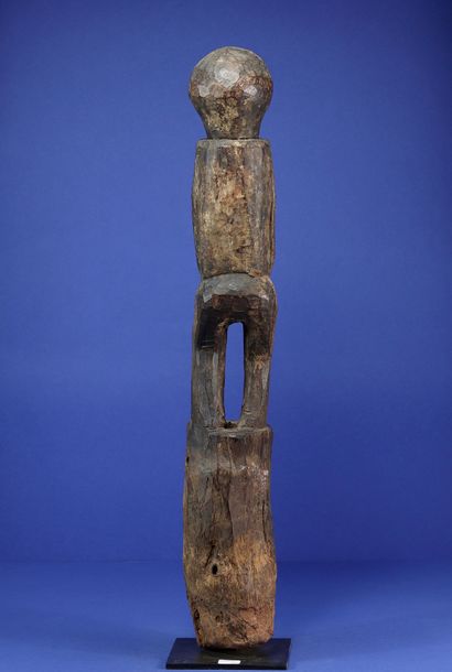 null 
Wooden botchio post representing a female figure standing on a truncated cone...