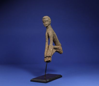 null 
Top of a divination stick showing a seated figure, arms joining the legs bent...