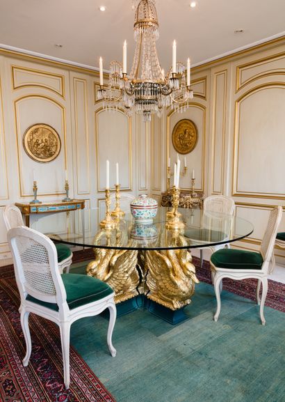 null Dining room table with glass top resting on four gilded metal swans leaning...