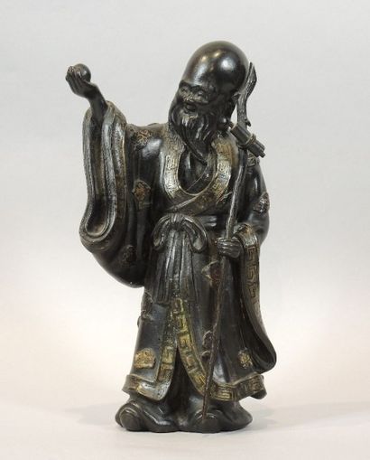 CHINE Statuette en bronze à patine noire et rehaut or représentant un sage tenant...