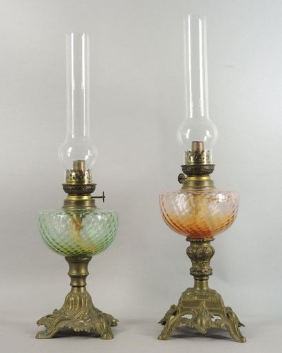 LAMPES Á PÉTROLE Deux lampes à pétrole corps en verre coloré et pieds en métal doré...