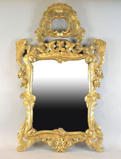 MIROIR DE STYLE BAROQUE Miroir de forme mouvmentée en bois sculpté et doré de rocailles,...