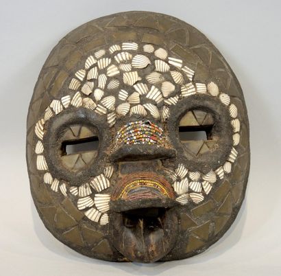 masque africain Masque africain de forme ronde en bois sculpté, fragments de coquillages,...