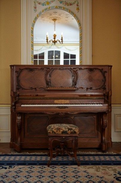 PIANO Piano droit en bois naturel mouluré et sculpté à décor de rocailles.
Travail...