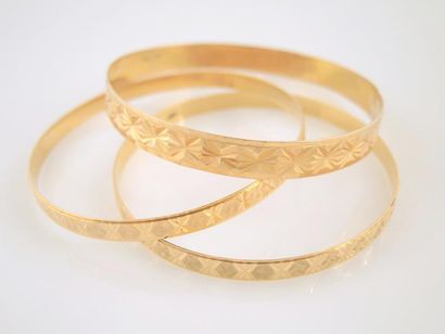 TROIS BRACELETS JONCS EN OR Trois bracelets ''jonc'' en or jaune 18K, à motifs d'étoiles...
