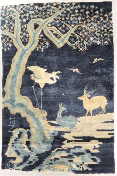 CHINE - XXe siècle Tapis en hauteur en laine sur fond bleu à décor de grue, biche...