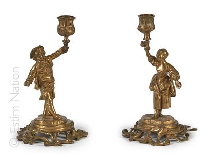 PAIRE DE BOUGEOIRS Paire de bougeoirs en métal doré à décor de personnages féminin...