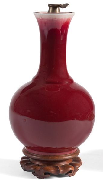 null Porcelain vase enamelled ox blood. It rests on a carved wooden base. Mounted...