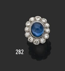 null Platinum marguerite ring, set with a cabochon sapphire in a setting of twelve...