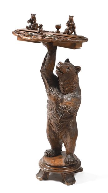 null Table écritoire en bois sculpté et patiné. Le fût à décor d'ours portant un...