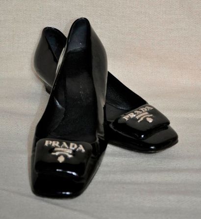 null PRADA. Paire de ballerines en cuir noir verni orné d'un emblème de la maison...