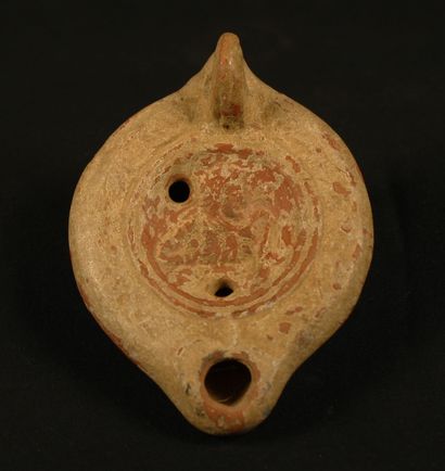 null 
Round oil lamp in terra cotta with heart-shaped spout and pierced handle decorated...