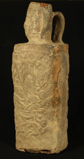 null Bottle in clear terracotta with a head-shaped neck and a body molded with scenes...