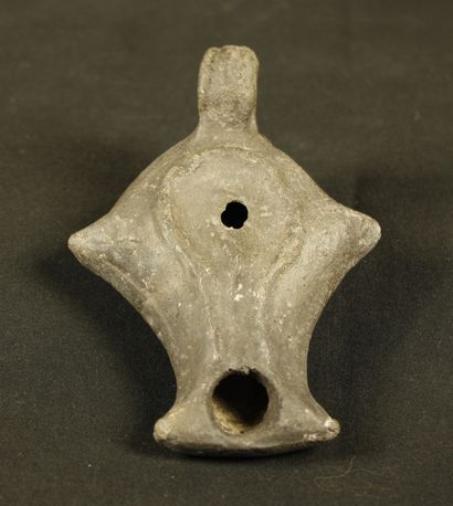 null Oil lamp in grey terra cotta with lateral horns and ribboned handle. The spout...