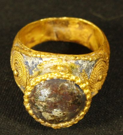 Gold ring setting a circular iridescent glass...