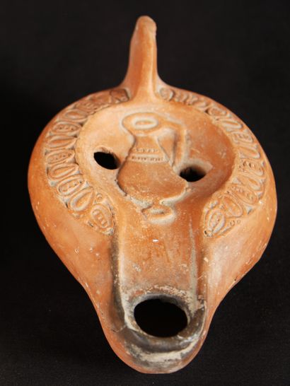 null Orange terracotta oil lamp with a curved channel decorated with a vase in the...