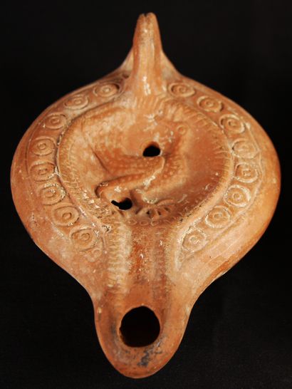 null Red terracotta lamp with curved channel decorated with a bird in the center...