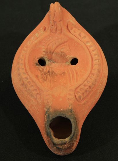 null Oil lamp in red clay with a curved channel and a small pierced handle decorated...