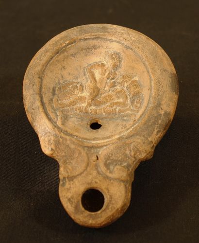 Terracotta oil lamp with round spout framed...