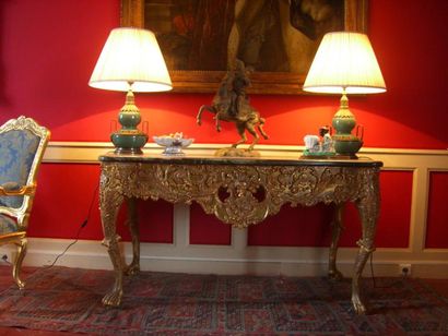  Table en bois sculpté et doré à décor de fleurs, feuillage et masques. Dessus en...