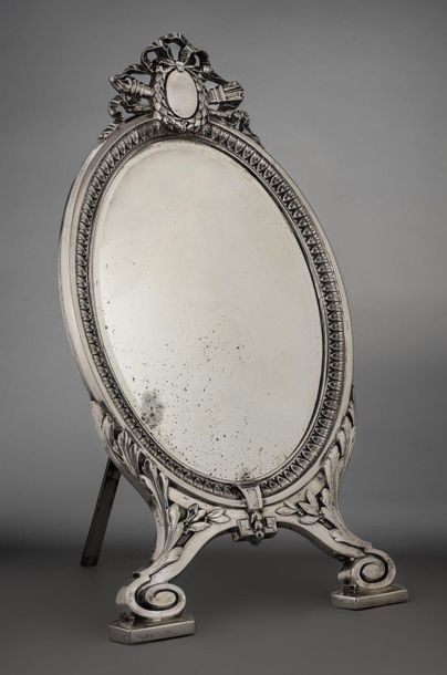 Silver oval table mirror on two scroll legs...