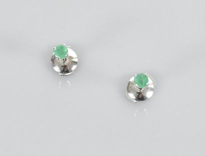 null White gold earrings, each decorated with a round emerald set with four claws,...