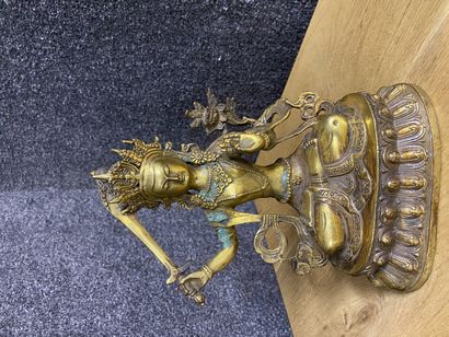 null 
Bouddha en bronze doré assis en position de méditation, la main droite tenant...