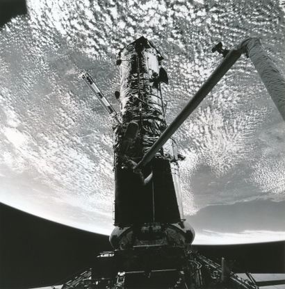 null NASA. HUBBLE TELESCOPE. In the shadow of HUBBLE, an astronaut held at the end...