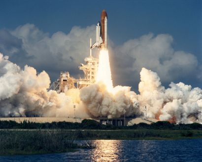 NASA NASA. The space shuttle Columbia rises like a golden tower in the royal blue...