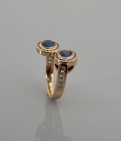 null Yellow gold cross ring, 750 MM, set with two oval sapphires each hemmed with...