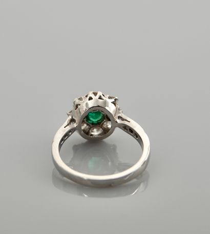 null White gold ring, 750 MM, set with a round emerald in a row of diamonds total...
