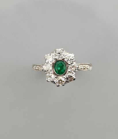 null White gold ring, 750 MM, set with a round emerald in a row of diamonds total...