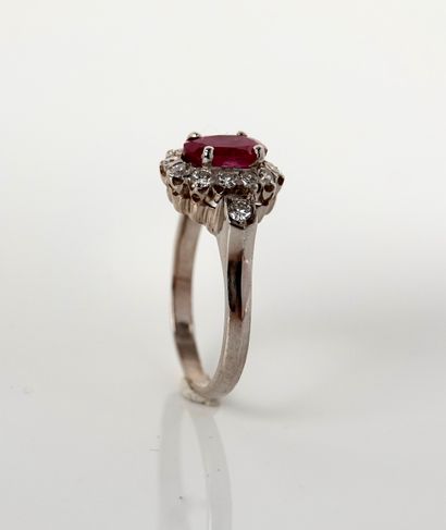 null Ring in white gold, 750 MM, centered by an oval ruby in a row of diamonds, can...