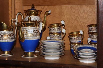 null Porcelain tea and coffee set with gold decoration on a blue background. One...