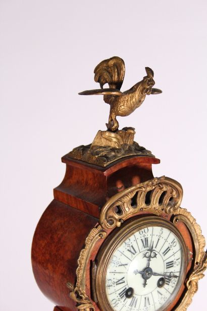 null A burr veneer and brass clock with rocaille decoration, topped by a rooster.

Louis...