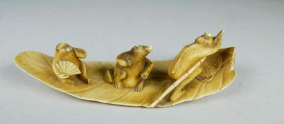 null Okimono en ivoire teinté représentant trois blaireaux navigant sur une feuille...