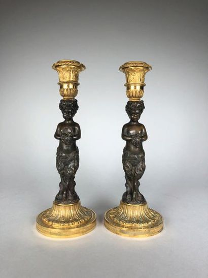 null Paire de flambeaux en bronze patiné et doré figurant des faunes. 
XIXe siècle....