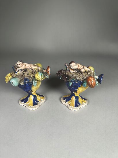 null Pair of polychrome glazed earthenware subjects depicting cherubs caressing a...