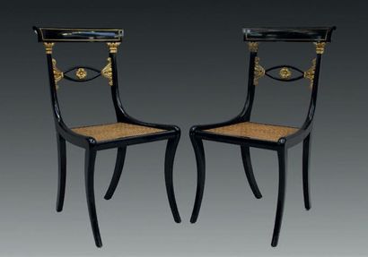 null Deux chaises en bois noirci et rehauts d'or.
Dossier à décor de chapiteau corinthien...
